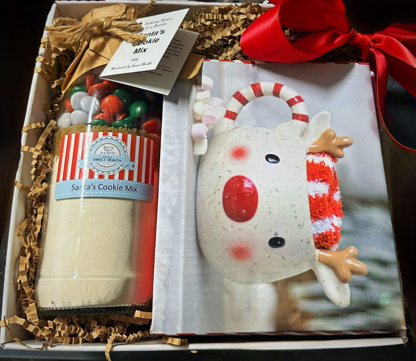 Gift set with a reindeer-themed candle and Santa's Cookie Mix in a decorative box.