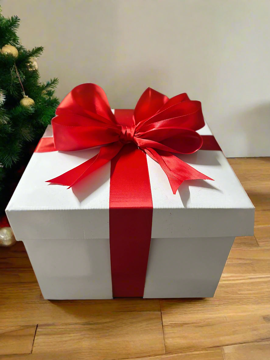 White gift box with a large red bow on a neutral background